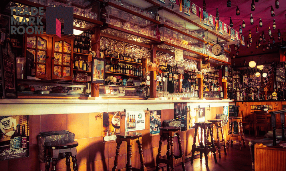 Bar interior with wooden stools, shelves filled with various drinks, and a welcoming atmosphere, relevant to trademark considerations for bar owners in London.