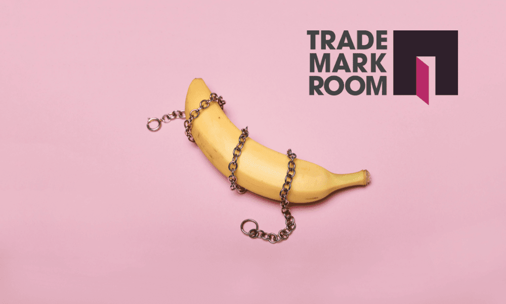 Banana wrapped in chains on pink background with Trademark Room logo, symbolising provocative branding and trademark challenges in erotic contexts.