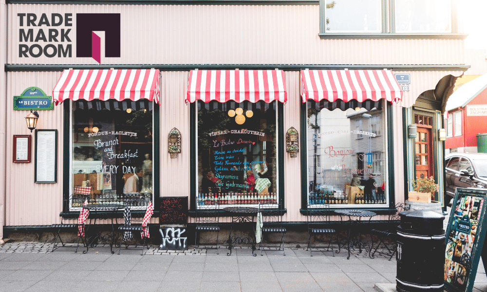 Bistro storefront with striped awnings, featuring "Brunch and Breakfast Every Day" sign, Trademark Room logo, and outdoor seating, symbolising small business branding and intellectual property protection.