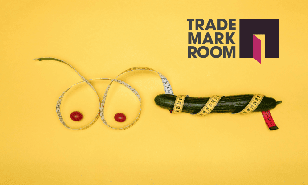 Cucumber wrapped in measuring tape, styled to resemble provocative imagery, with red tomatoes representing breasts, on a bright yellow background, featuring the Trademark Room logo, illustrating adult branding concepts.