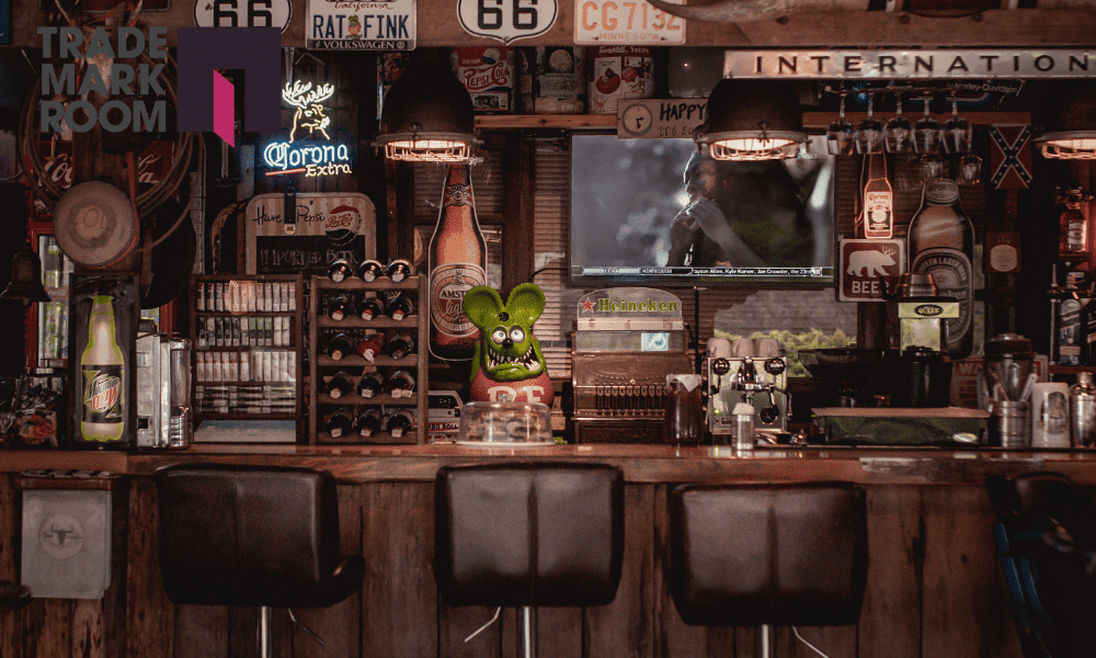 Bar interior showcasing various alcoholic and non-alcoholic beverages, including Corona and Heineken signage, with a vibrant green mascot character, reflecting the hospitality industry and brand identity considerations for bar owners in London.
